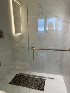 Professional move-out deep cleaning service in Championsgate, FL, featuring a spotless glass shower door and sanitized bathroom stall by Velura Clean.